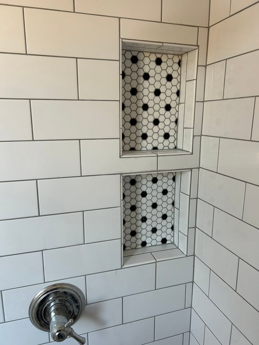 Tiled Shower Niches: Recessed niches with black-and-white hex accent tile.
