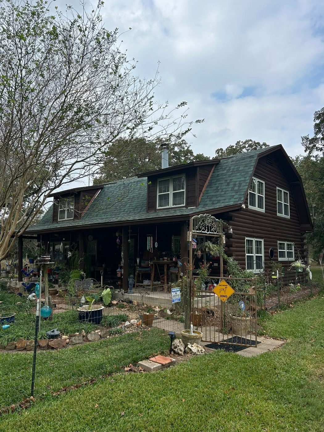 New Roof on a Log Home: Green architectural shingles on a gambrel roof with dormers.