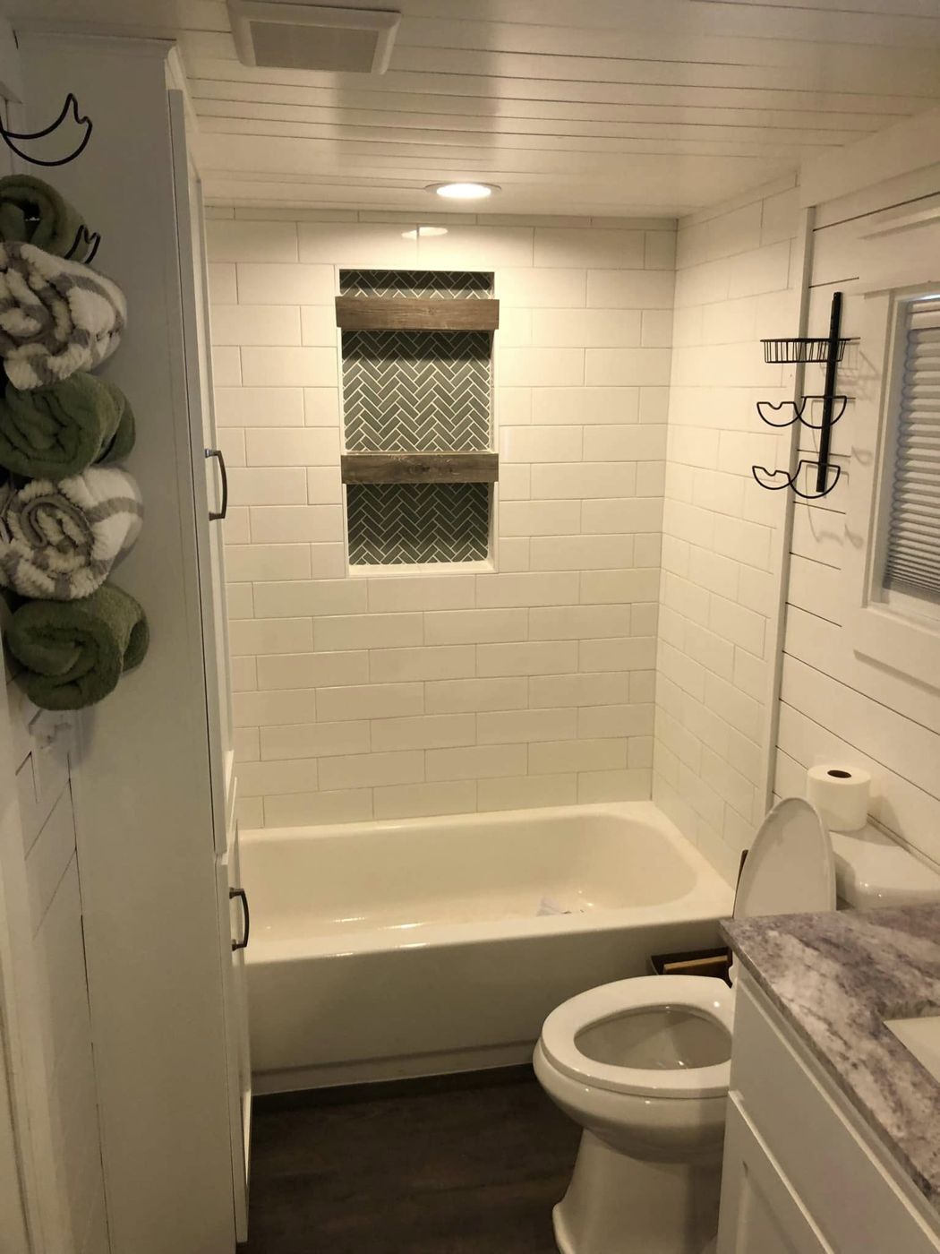 Tiny House Bathroom: Subway tile tub surround with a herringbone niche and wood shelves.