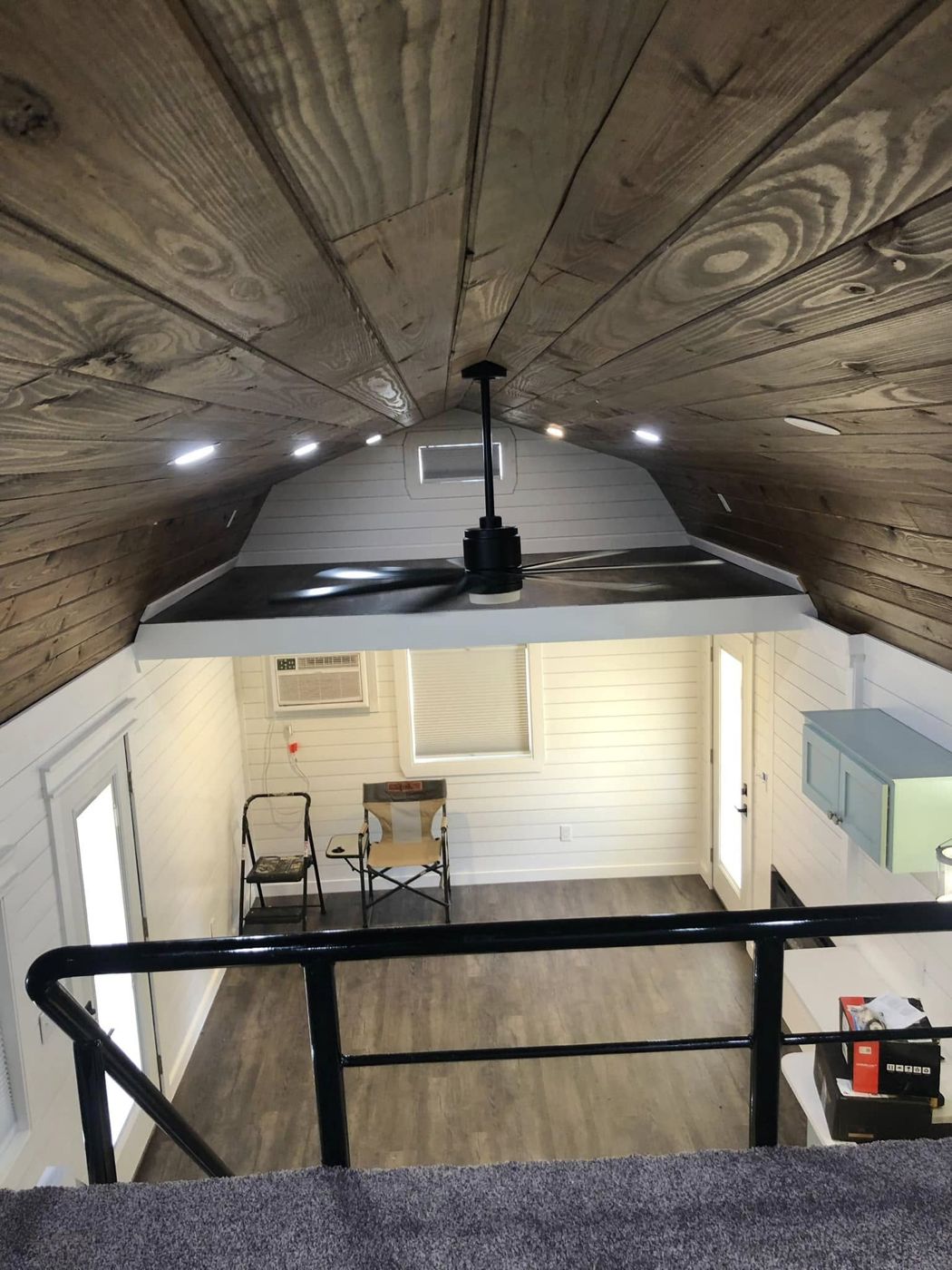View From the Loft: Stained plank ceiling with recessed lights and a ceiling fan over the living area.