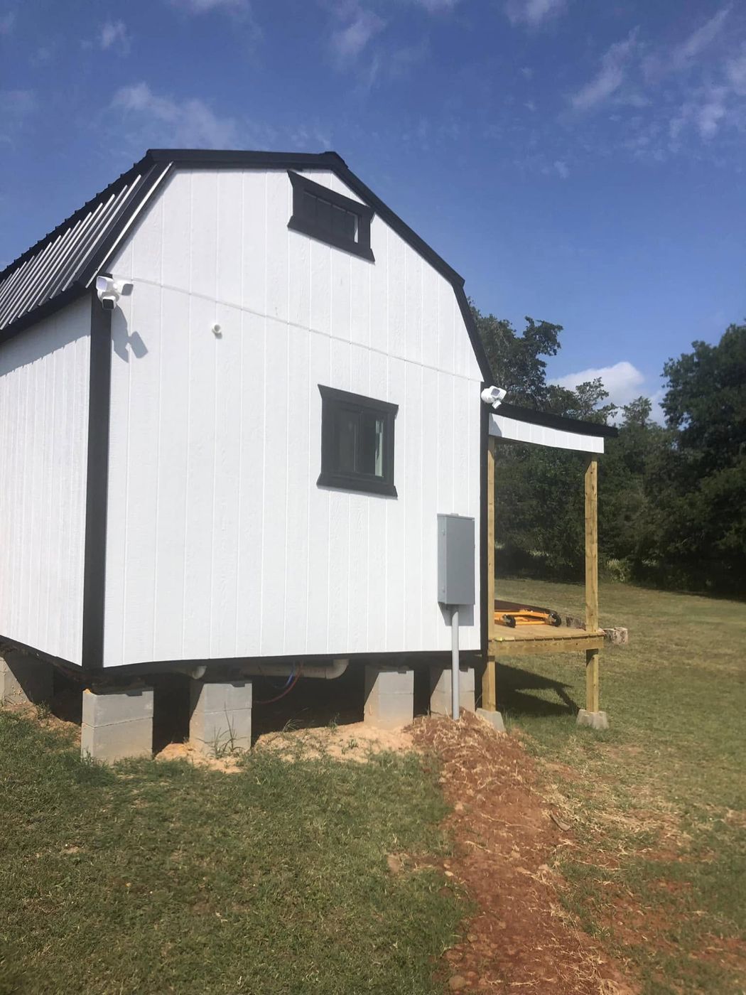 Tiny House Exterior: Fresh white siding with black trim, a metal roof and a covered side porch.